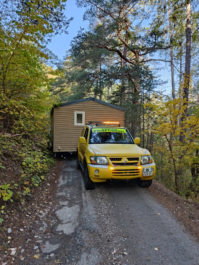 Voiture-pilote guidant un mobil-home sur une route étroite